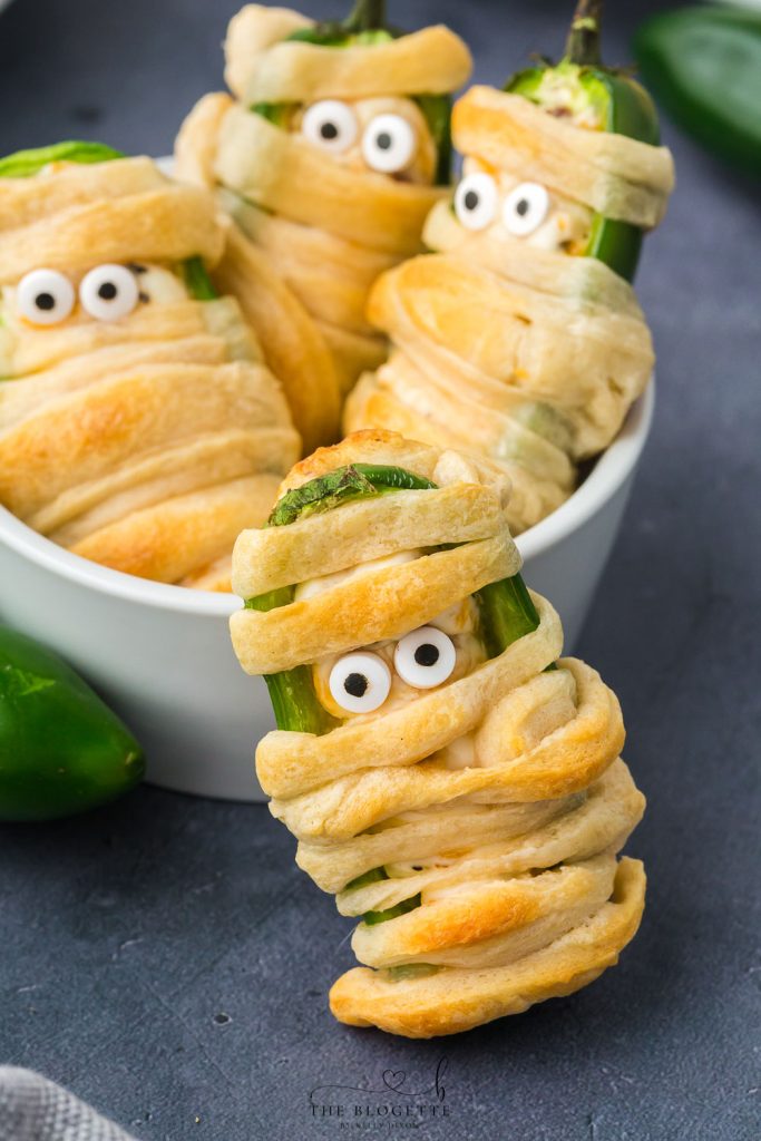 Halloween Jalapeño Popper Mummies are adorably spooky jalapeños, filled with a cream cheese mixture, wrapped in crescent dough, and baked!