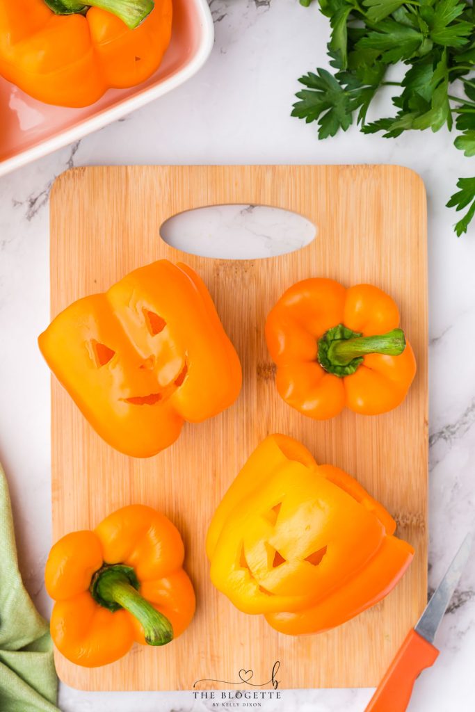 Orange bell peppers carved into jack o lantern pumpkins and stuffed with ground beef and rice for Halloween!