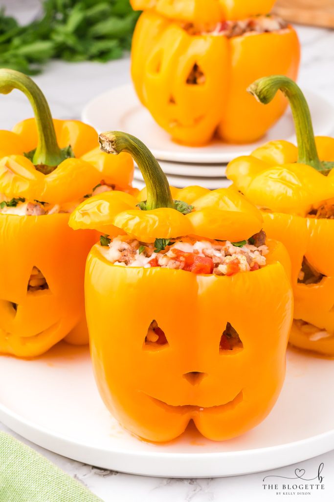 Orange bell peppers carved into jack o lantern pumpkins and stuffed with ground beef and rice for Halloween!