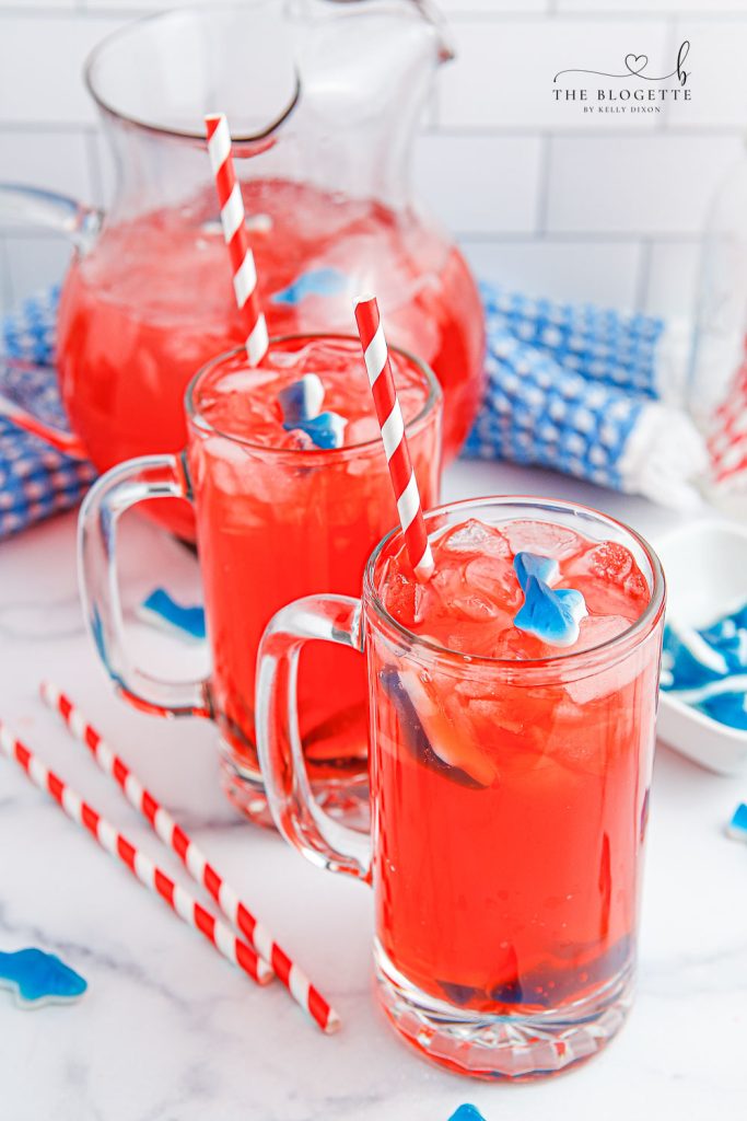 Shark Attack Punch or mocktail is the ultimate summertime drink! Tasty red punch served with floating shark gummies. Shark Punch is perfect for Shark Week or beach-themed parties!