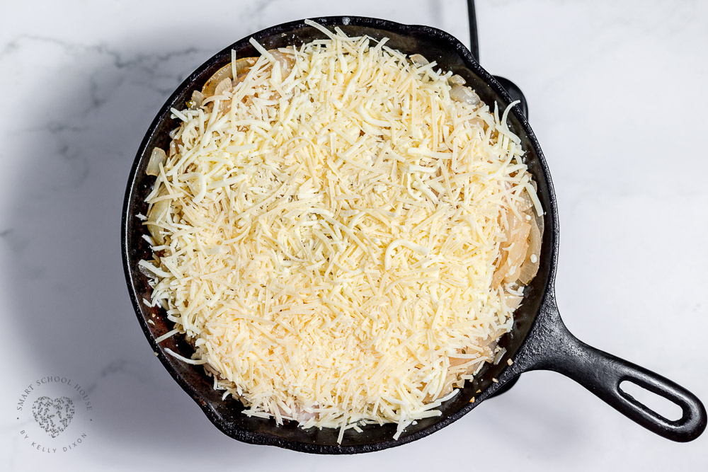 Shredded cheese on top of chicken and onions